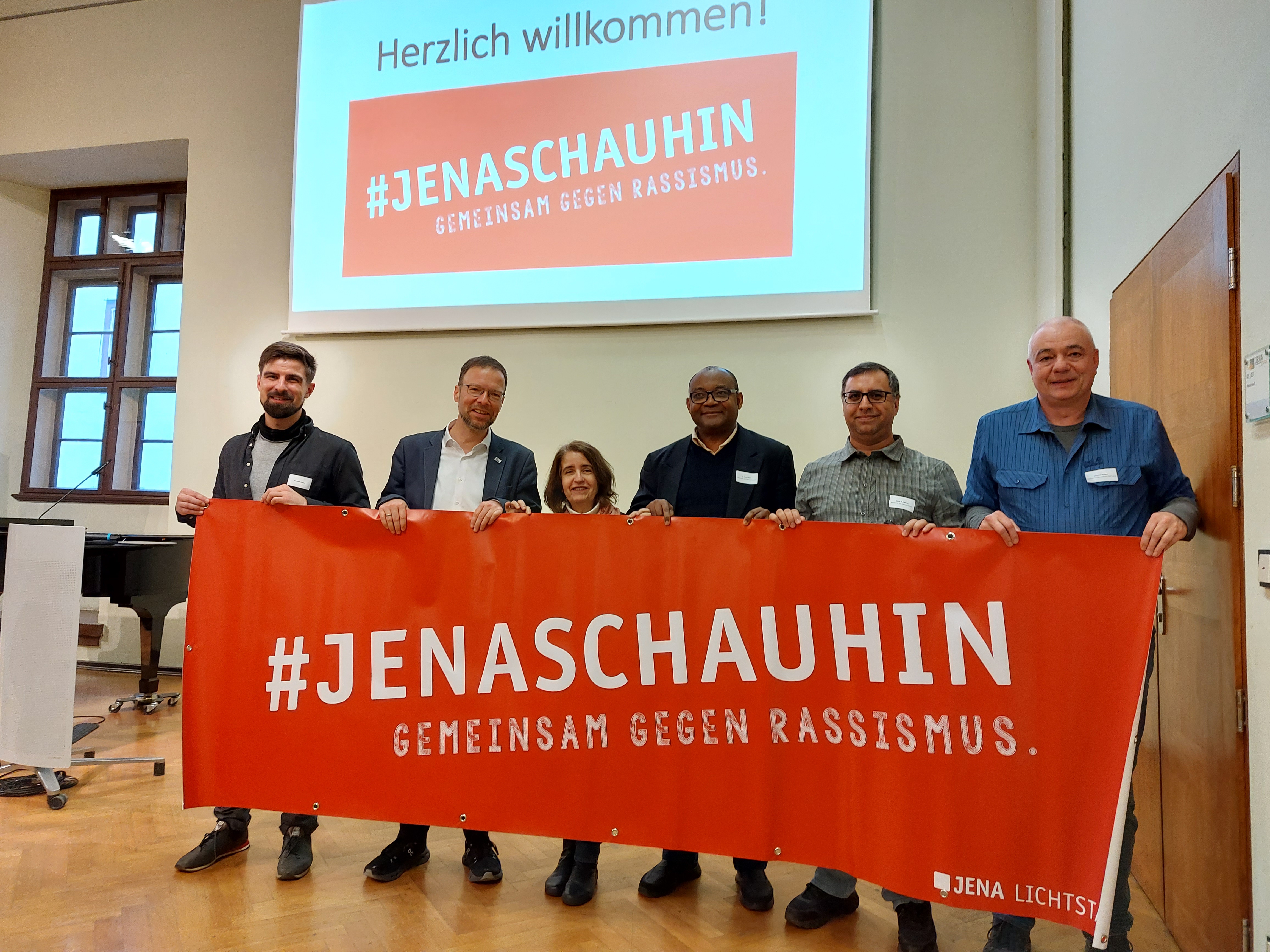 6 Personen stehen nebeneinander und halten ein Transparent mit dem Schriftzug #Jenaschahin, Gemeinsam gegen Rassismus